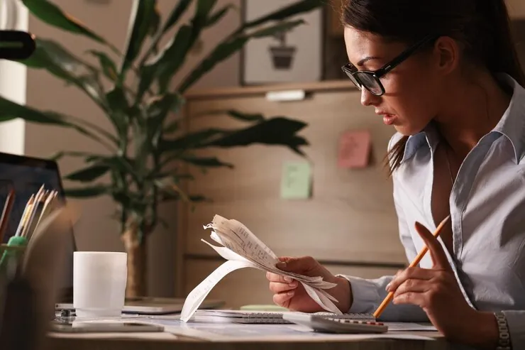 Accountant with glasses checking receipts and calculating figures at the office